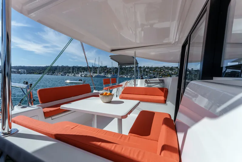 In Stock #169 Yacht Photos Pics Luxurious 2024 Excess 11 catamaran with vibrant orange seating and scenic ocean view.