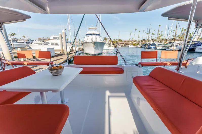In Stock #169 Yacht Photos Pics 2024 Excess 11 yacht with orange seating, docked at a marina.