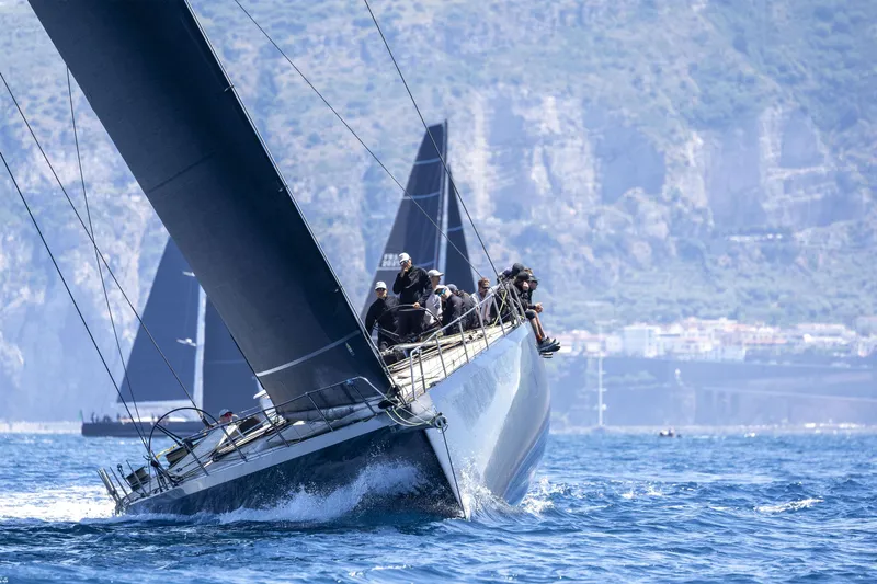 Bullitt Yacht Photos Pics Sailing yacht Wally Custom 2018 navigating blue waters with crew, mountainous backdrop.