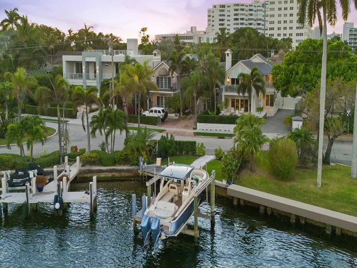  Yacht Photos Pics 2023 Chris-Craft Launch 31 GT docked by waterfront homes, surrounded by lush greenery.