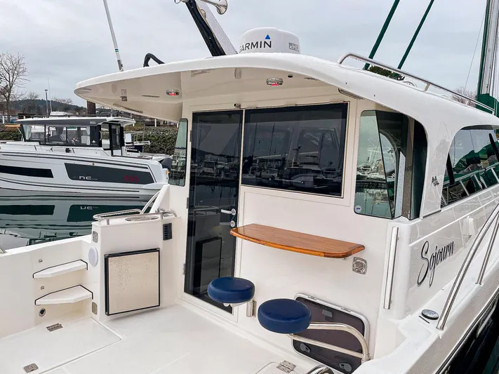 Sojourn Yacht Photos Pics Aspen C108 2022 boat with seating and table on deck, docked at marina.