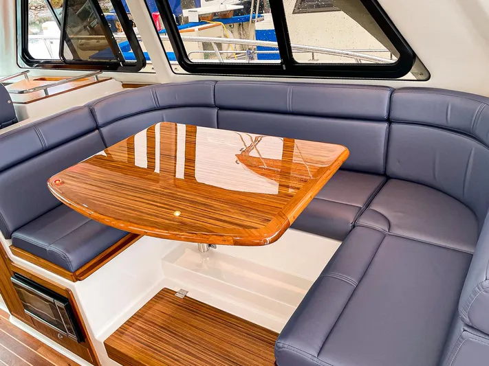 Sojourn Yacht Photos Pics Luxurious interior of 2022 Aspen C108 boat with sleek wood table and cushioned seating.