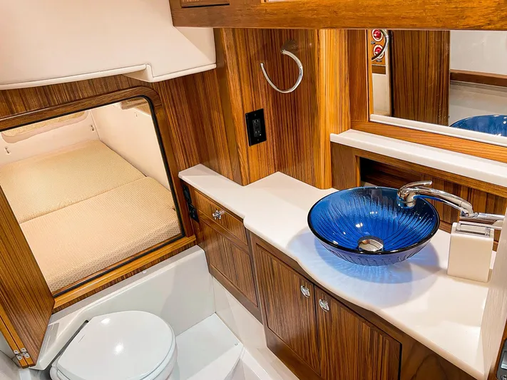 Sojourn Yacht Photos Pics Luxurious Aspen C108 2022 yacht interior with wooden cabinetry and modern blue glass sink.
