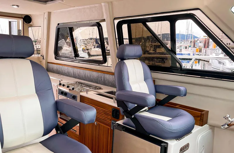 Sojourn Yacht Photos Pics Interior of 2022 Aspen C108 boat with blue and white seating, docked at marina.