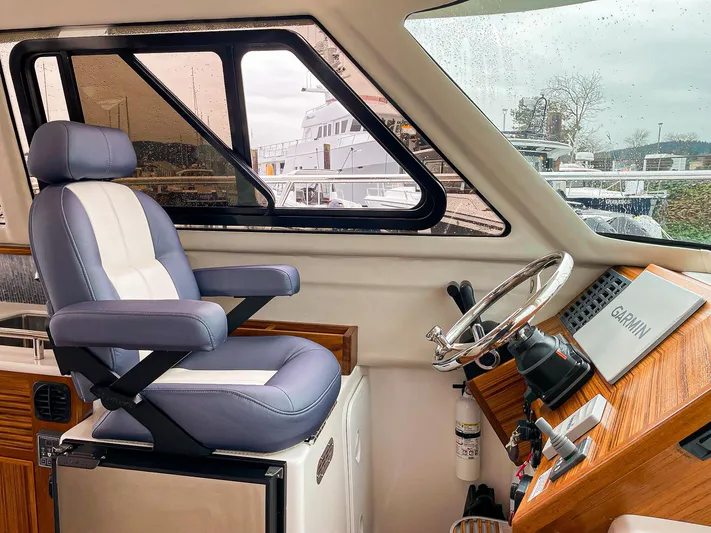 Sojourn Yacht Photos Pics Captain's seat in 2022 Aspen C108 boat cockpit with steering wheel and navigation equipment.