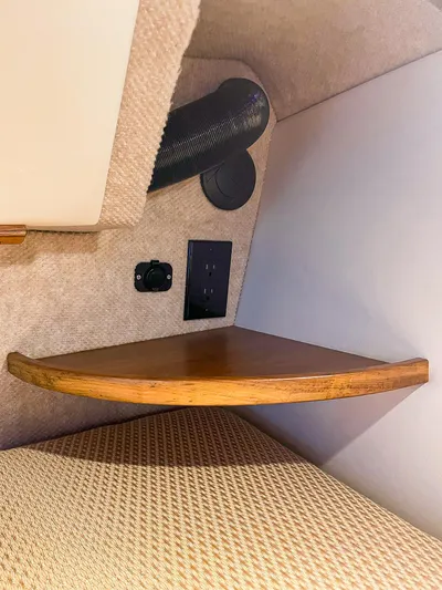 Sojourn Yacht Photos Pics 2022 Aspen C108 interior with wooden shelf, power outlet, and beige upholstery.