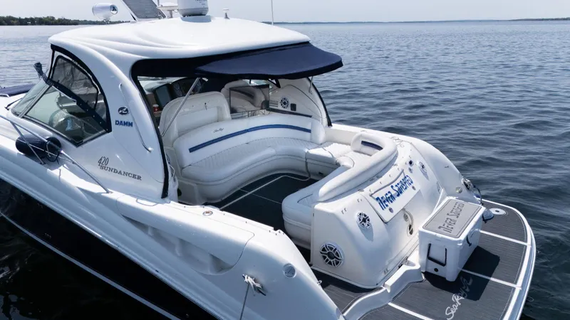  Yacht Photos Pics 2005 Sea Ray 420 Sundancer yacht with spacious deck, white seating, and blue canopy on calm water.