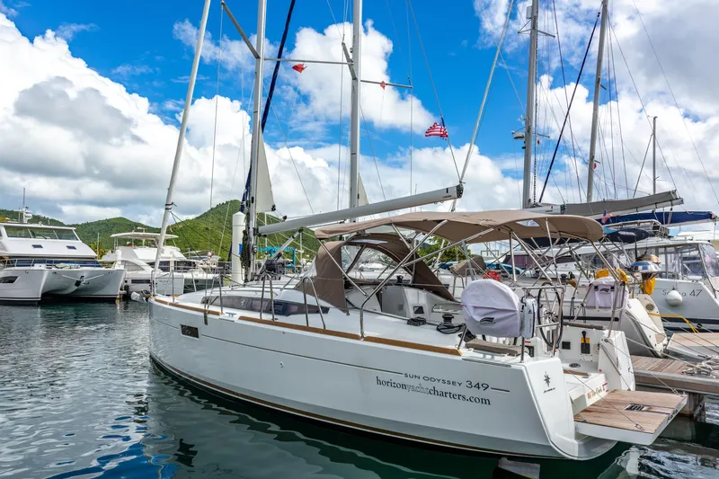 Off The Clock Yacht Photos Pics 2020 Jeanneau Sun Odyssey 349 sailboat docked in a marina under a blue sky.