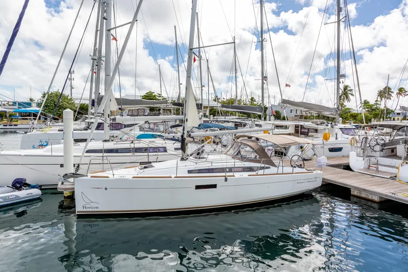 Off The Clock Yacht Photos Pics 2020 Jeanneau Sun Odyssey 349 sailboat docked in a marina under a partly cloudy sky.