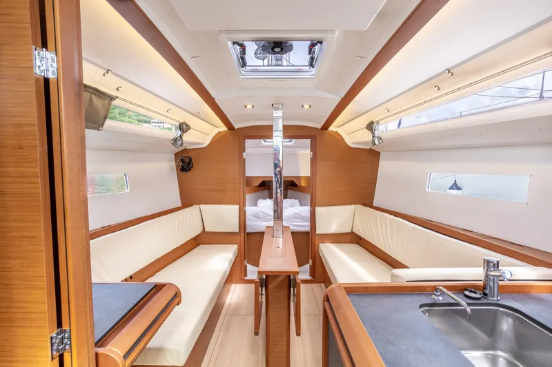 Off The Clock Yacht Photos Pics Interior of 2020 Jeanneau Sun Odyssey 349 sailboat, featuring modern wood and white seating.