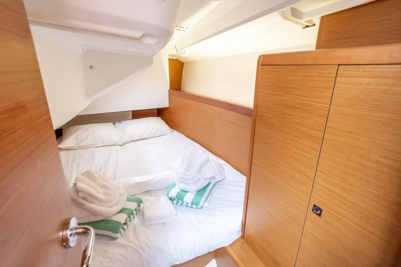 Off The Clock Yacht Photos Pics Cozy cabin interior of 2020 Jeanneau Sun Odyssey 349 with neatly arranged bed and towels.