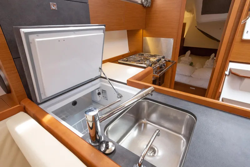 Off The Clock Yacht Photos Pics Modern kitchen area in 2020 Jeanneau Sun Odyssey 349 yacht, featuring sink and stove.