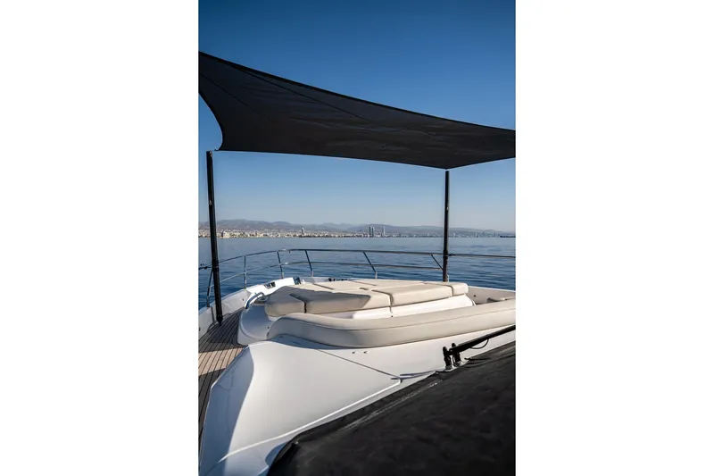  Yacht Photos Pics Luxurious 2023 Princess Y72 yacht deck with sunshade, overlooking serene ocean and distant cityscape.