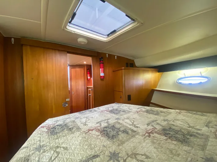 Details Yacht Photos Pics 1998 Tiara Yachts 35 Open cabin interior with bed, wooden walls, and porthole window.