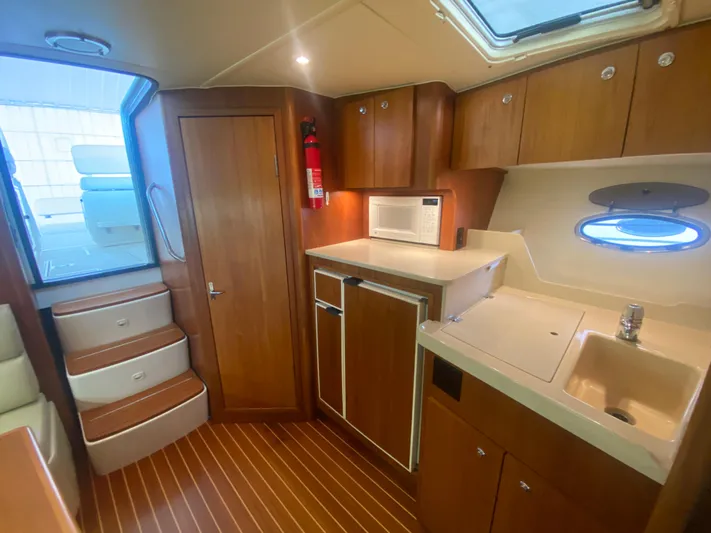 Details Yacht Photos Pics 1998 Tiara Yachts 35 Open interior with kitchenette, wooden cabinets, and stairs.