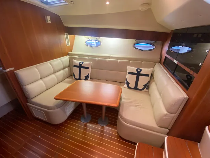 Details Yacht Photos Pics 1998 Tiara Yachts 35 Open interior with beige seating, anchor-themed pillows, and wooden table.