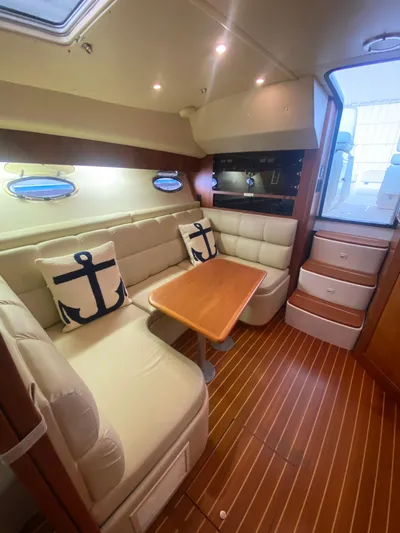 Details Yacht Photos Pics 1998 Tiara Yachts 35 Open interior with cozy seating, anchor-themed pillows, and wooden flooring.
