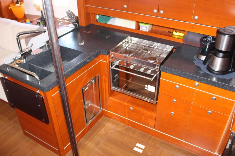  Yacht Photos Pics 2010 Hanse 545 yacht kitchen with wooden cabinets, stove, sink, and coffee maker.