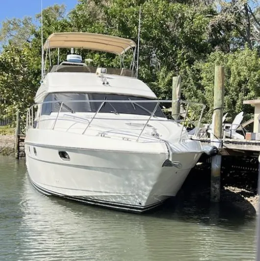 My Girls Too Yacht Photos Pics 1998 Viking Princess 46 Flybridge Sport Cruiser docked by lush greenery.
