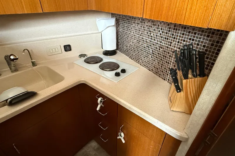  Yacht Photos Pics Compact kitchen in 1999 Ocean Yachts 40 Express, featuring stove, sink, and knife set.