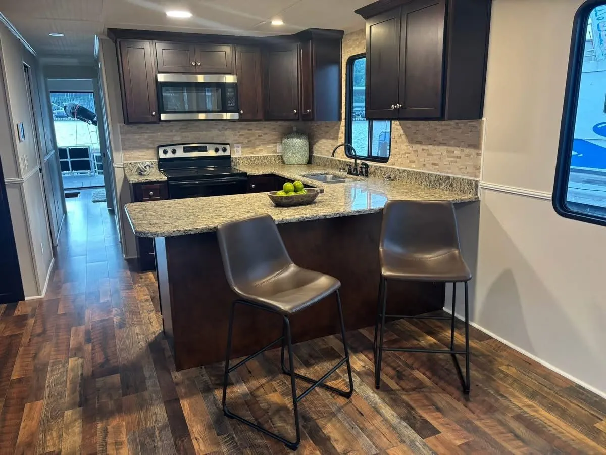 Modern kitchen interior of 1992 Lakeview houseboat with granite countertops and wooden flooring.
