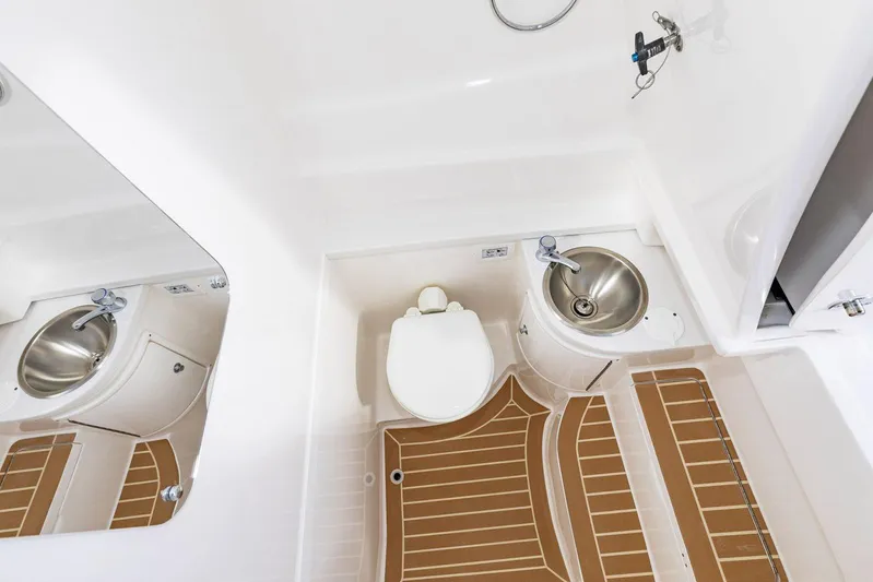  Yacht Photos Pics Manufacturer Provided Image: 2022 Intrepid 345 Nomad FE boat bathroom with toilet, sink, and wooden floor mat.