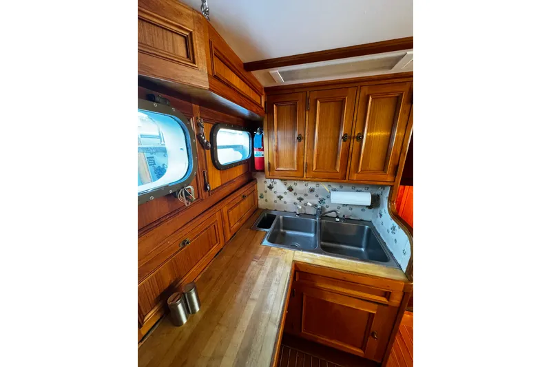  Yacht Photos Pics Wooden kitchen interior of 1974 Doggersbank 63 boat with double sink and porthole windows.