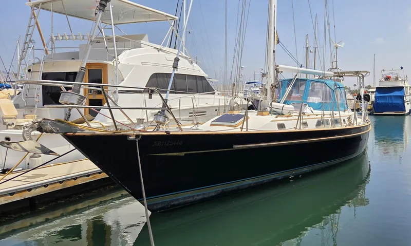  Yacht Photos Pics 1987 Tayana Center Cockpit sailboat docked in marina, featuring sleek design and blue canopy.