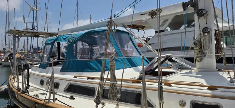  Yacht Photos Pics 1987 Tayana Center Cockpit sailboat docked in marina, featuring blue canopy and rigging.