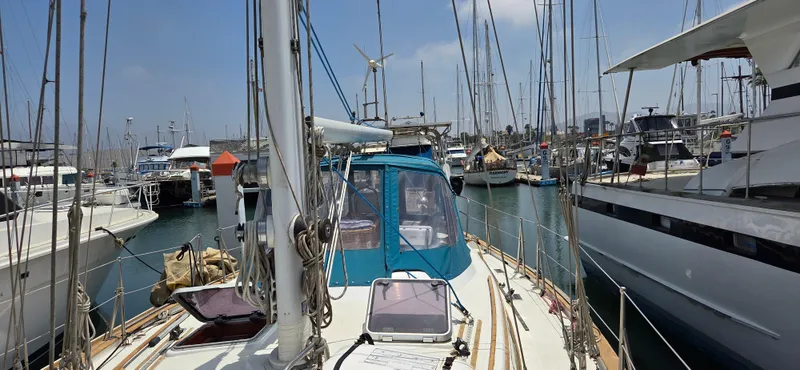  Yacht Photos Pics 1987 Tayana Center Cockpit sailboat docked in a busy marina, surrounded by other boats.