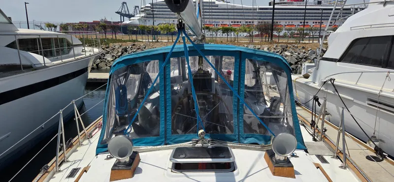  Yacht Photos Pics 1987 Tayana Center Cockpit sailboat docked at marina with cruise ship in background.