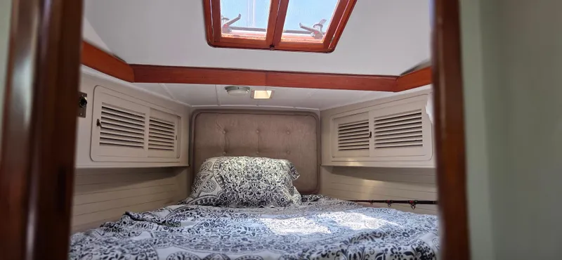  Yacht Photos Pics Cozy cabin interior of 1987 Tayana Center Cockpit sailboat with skylight and patterned bedding.