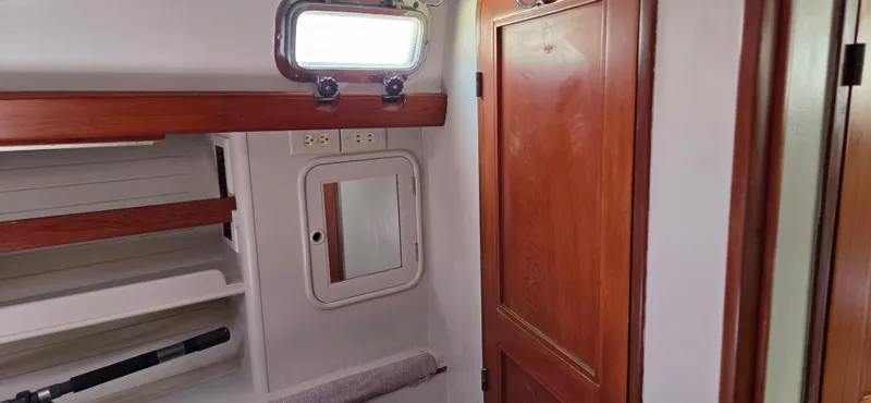  Yacht Photos Pics 1987 Tayana Center Cockpit interior with wooden door, shelves, and porthole window.