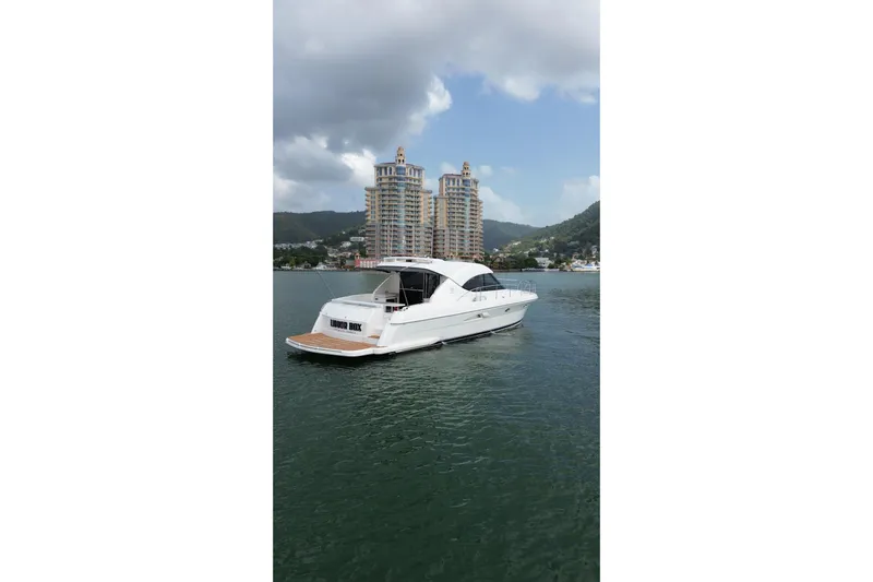  Yacht Photos Pics 2009 Riviera 4700 Sport Yacht on water with scenic cityscape background.