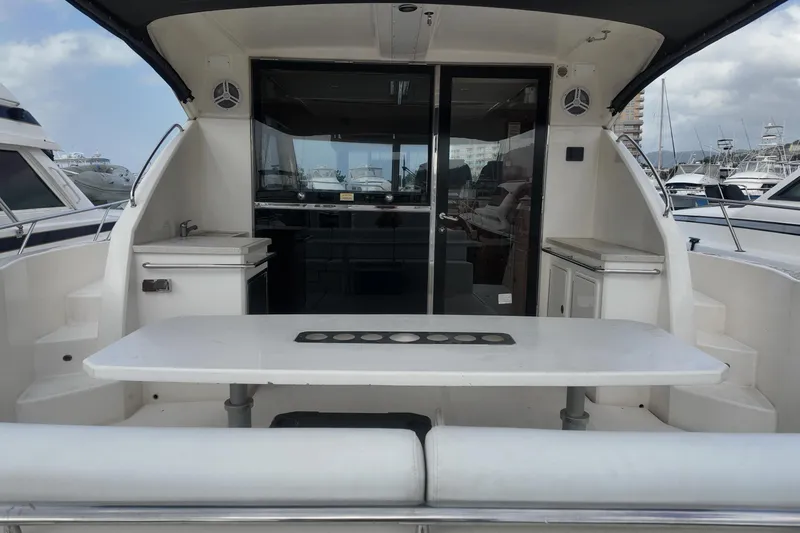  Yacht Photos Pics 2009 Riviera 4700 Sport Yacht, rear deck view with table and seating, docked at marina.