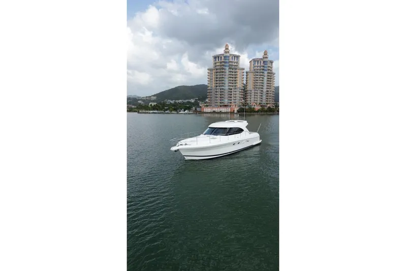  Yacht Photos Pics 2009 Riviera 4700 Sport Yacht cruising on a calm lake with cityscape backdrop.