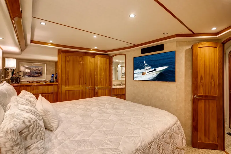 Pipe Dreamer Yacht Photos Pics Luxurious bedroom interior of 2015 Viking 70 Convertible yacht with wood accents and TV.