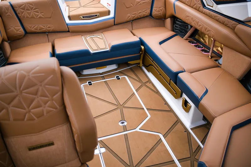  Yacht Photos Pics Luxurious interior of 2024 Nautique Super Air Nautique G23 Paragon boat, featuring tan and blue seating.