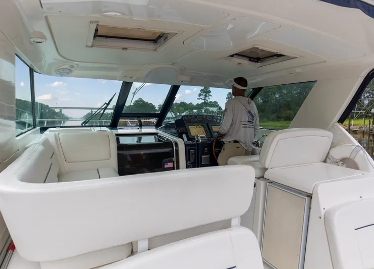 Forever Friday Yacht Photos Pics 2005 Tiara Yachts 3600 Sovran interior with captain at helm, featuring white seating and navigation equipment.