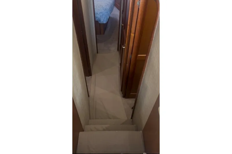 Offshore Obsession Yacht Photos Pics Interior hallway of a 1998 Ocean 53 Convertible yacht, featuring wooden doors and carpeted flooring.