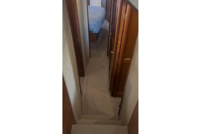 Offshore Obsession Yacht Photos Pics Narrow hallway inside 1998 Ocean 53 Convertible yacht, featuring wooden cabinetry and carpeted flooring.