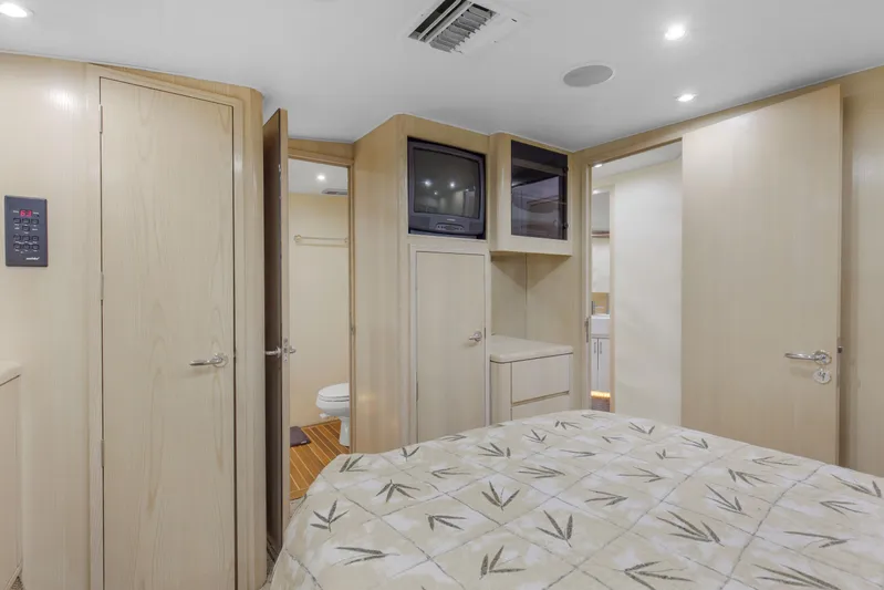 Fatso Yacht Photos Pics 1998 Hatteras 60 Convertible yacht bedroom with TV, wood cabinetry, and patterned bedding.