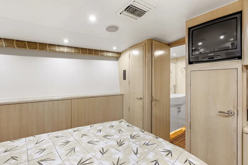 Fatso Yacht Photos Pics Bedroom interior of 1998 Hatteras 60 Convertible yacht with TV and patterned bedding.
