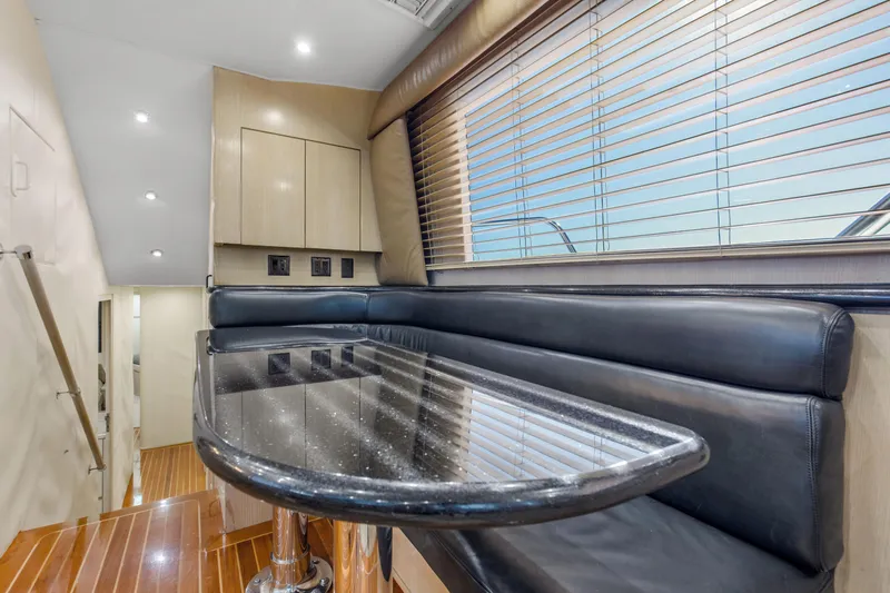 Fatso Yacht Photos Pics Interior of 1998 Hatteras 60 Convertible yacht with sleek dining area and wooden flooring.
