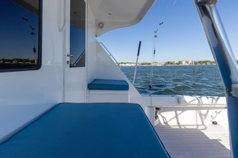 Fatso Yacht Photos Pics 1998 Hatteras 60 Convertible yacht deck with blue seating, overlooking calm waters.