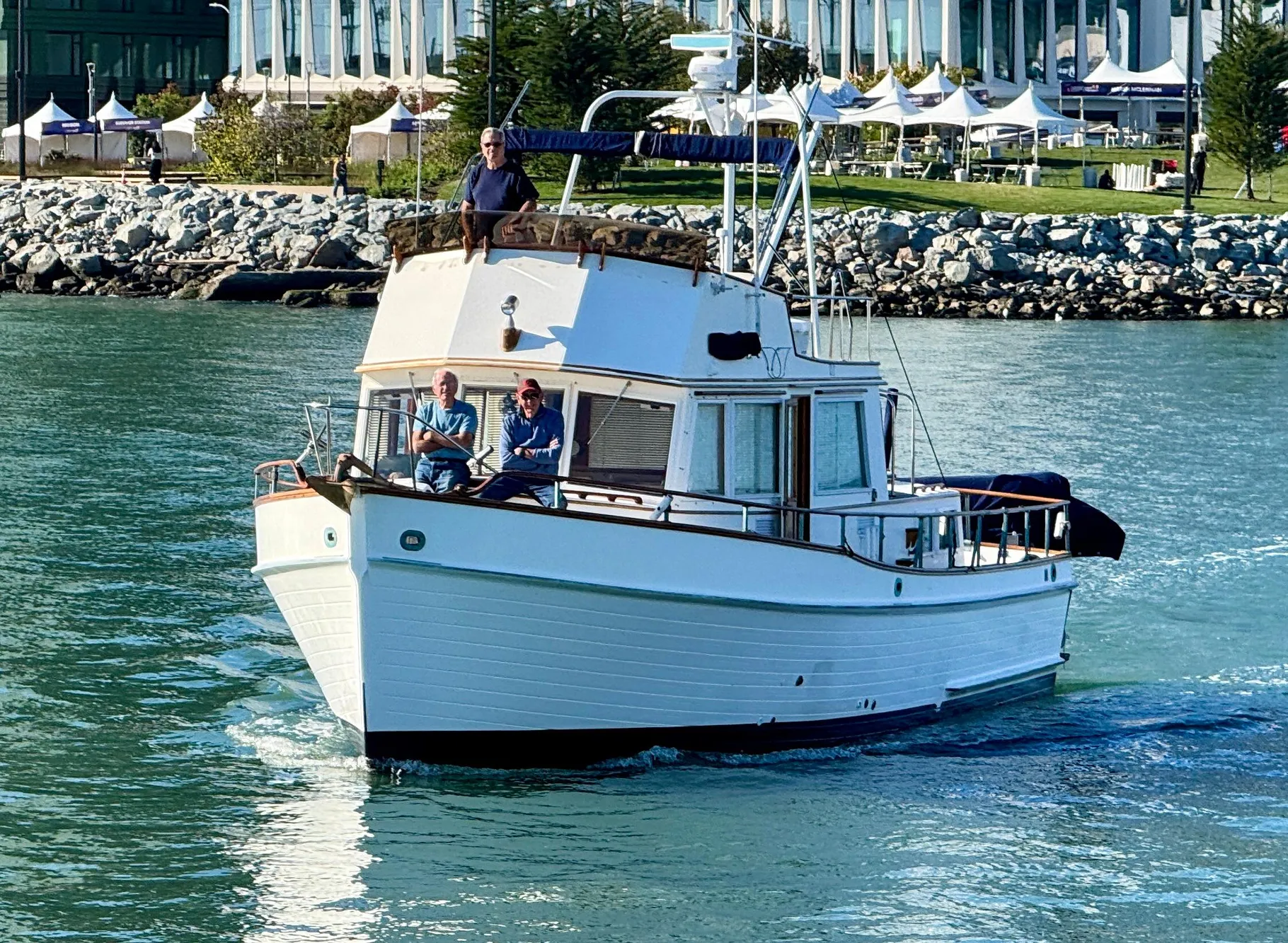 1979 Grand Banks Classic boat cruising near a rocky shoreline.