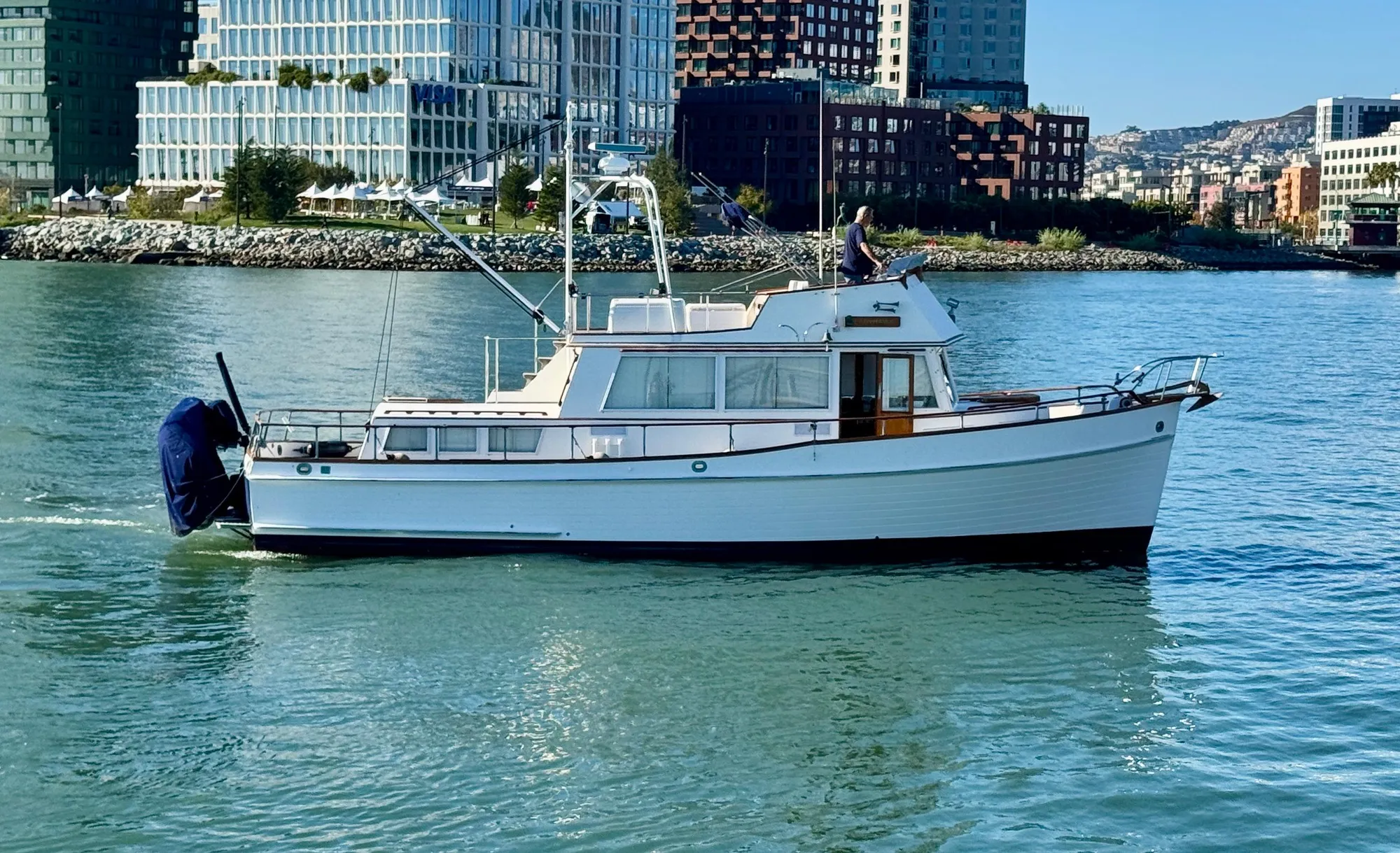1979 Grand Banks Classic yacht cruising in urban waterfront setting.