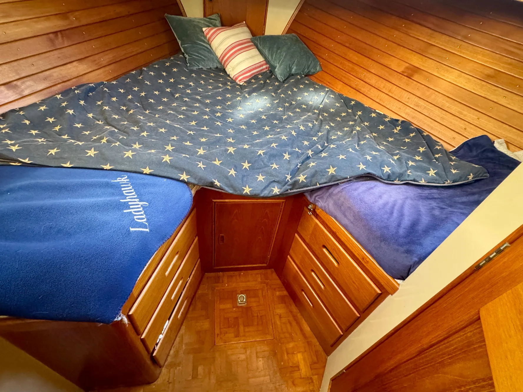 Cozy 1979 Grand Banks Classic cabin with star-patterned bedding and wooden storage drawers.
