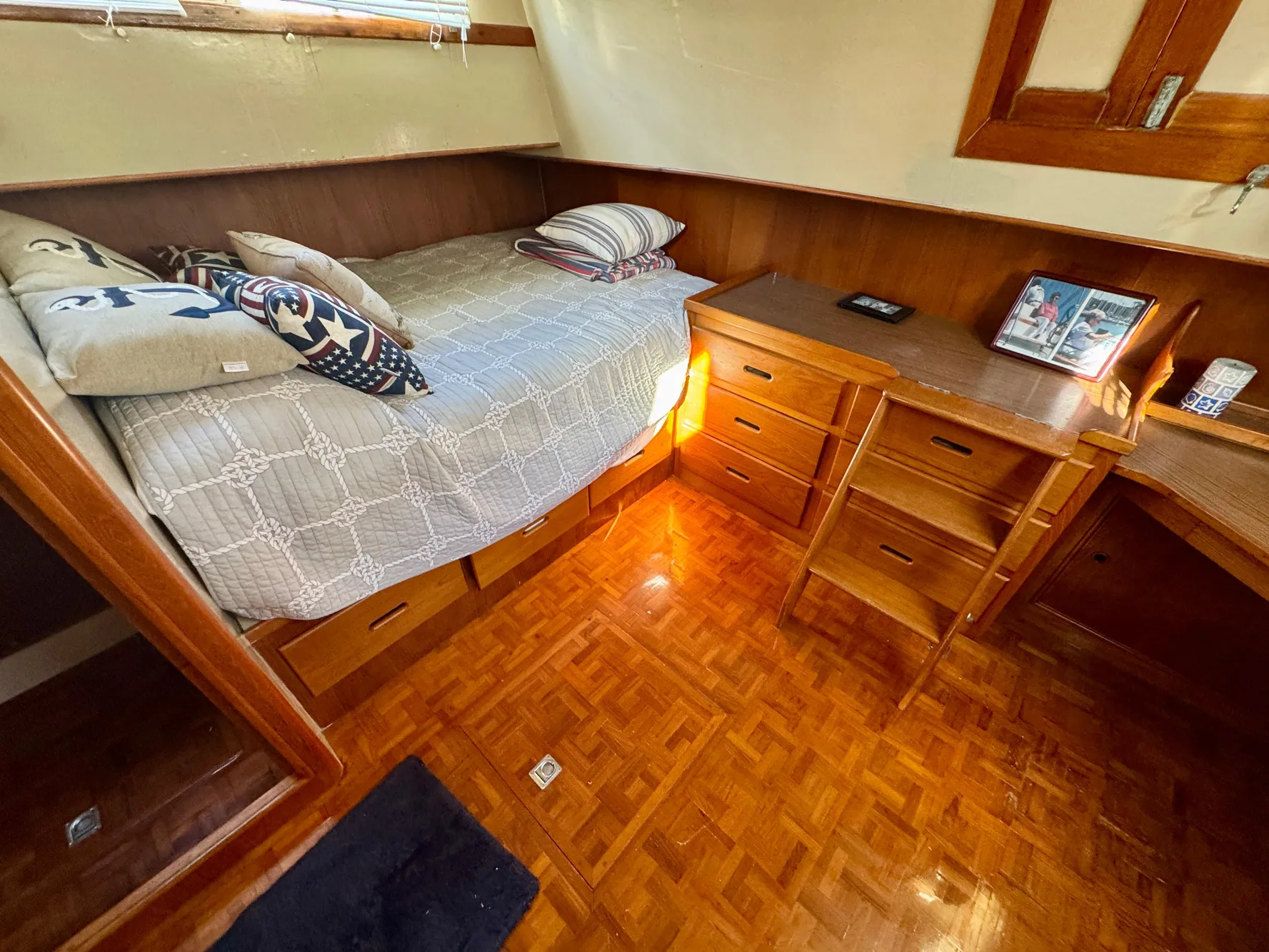 Cozy cabin interior of 1979 Grand Banks Classic with bed, wooden desk, and parquet flooring.