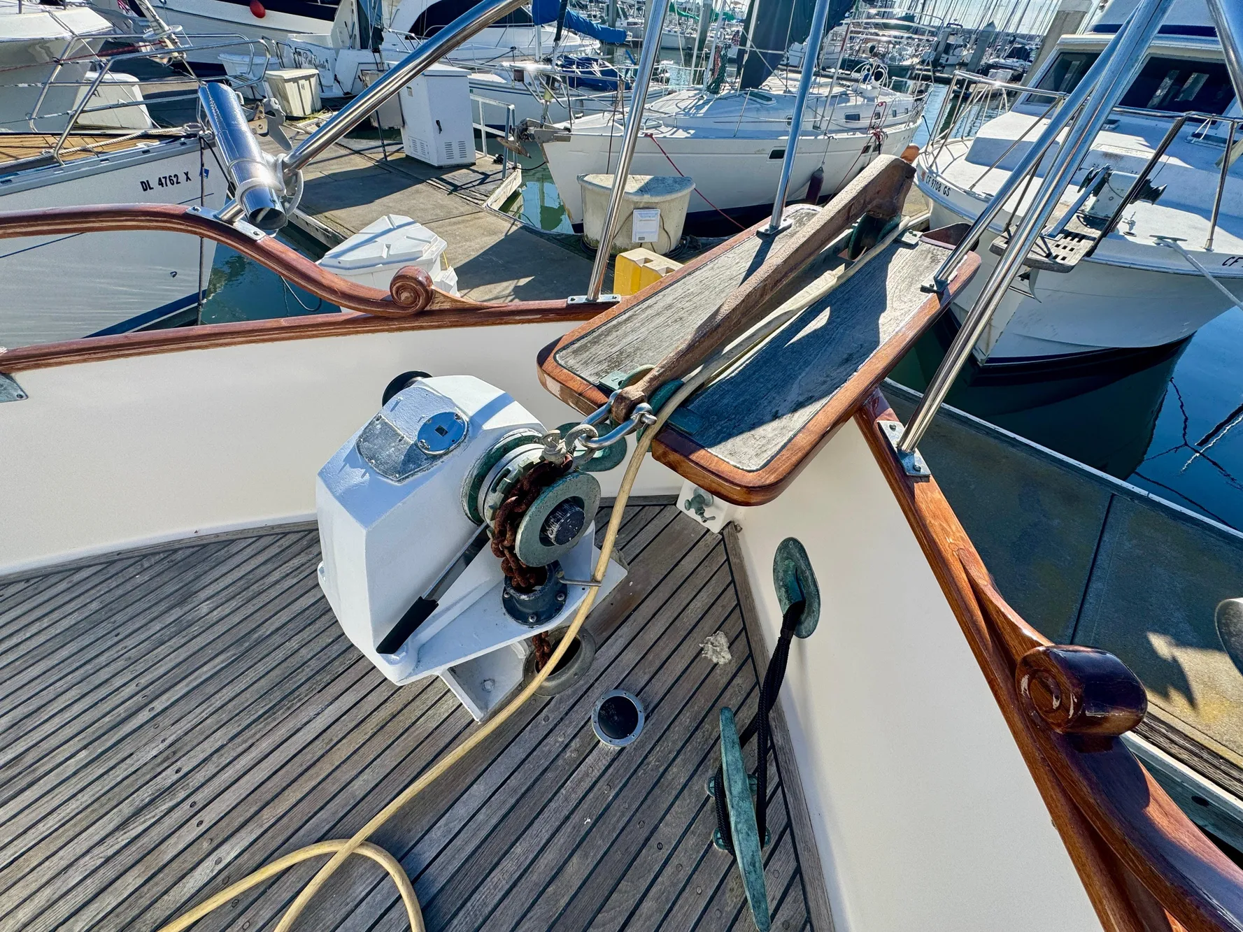 1979 Grand Banks Classic yacht deck with anchor winch and wooden railings in marina.